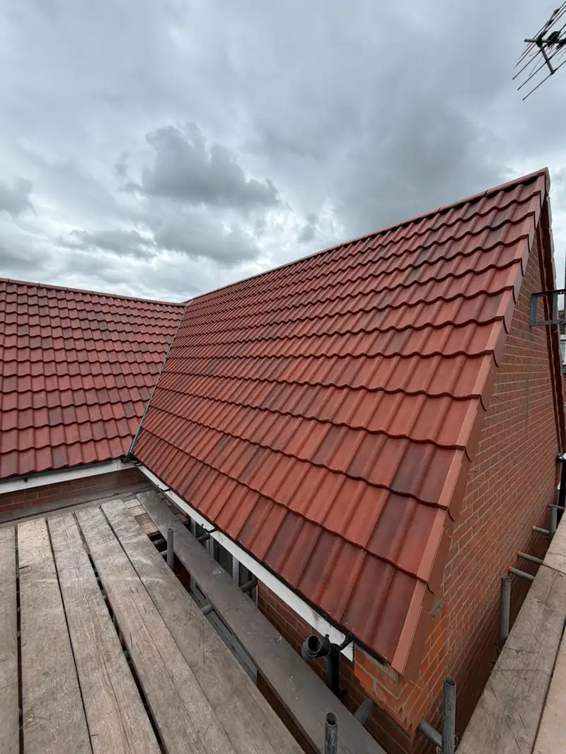 New red interlocking tiles and dry verge on a gable of the Bourne re-roof